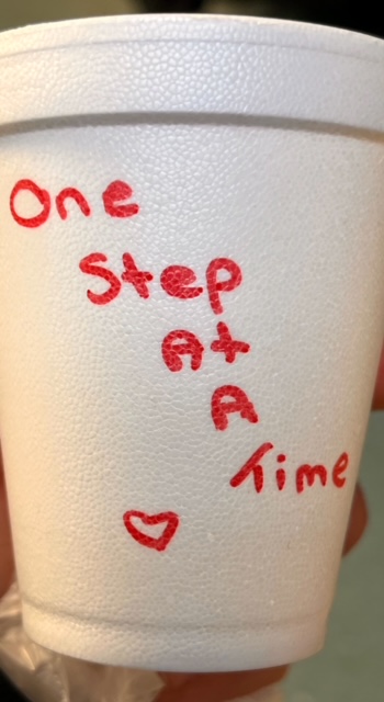 A cup marked One Step At A Time, reflecting practical encouragement